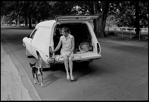 An off-duty cleaner walks her dog from the back of a station wagon, in Centennial Park, Sydney © Rob Walls 1977 